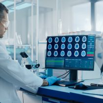 Stock image: A male neurobiologist working on a computer with a display showing neuroimaging of a brain with scans, symbolising current substudies at AIBL.